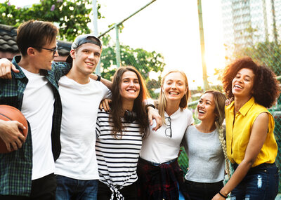 Smiling happy young adult friends arms around shoulder outdoors friendship and connection concept