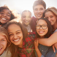 Teenage school friends smiling to camera, close up
