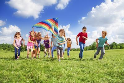 Large group of beautiful kids boys and girls running with kids in the park