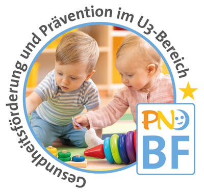 Zwei Kleinkinder sitzen gemeinsam auf dem Boden und spielen mit Holzringen.