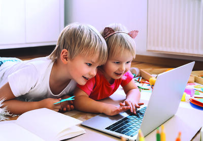 Zwei Kinder sitzen vor einen Laptop.
